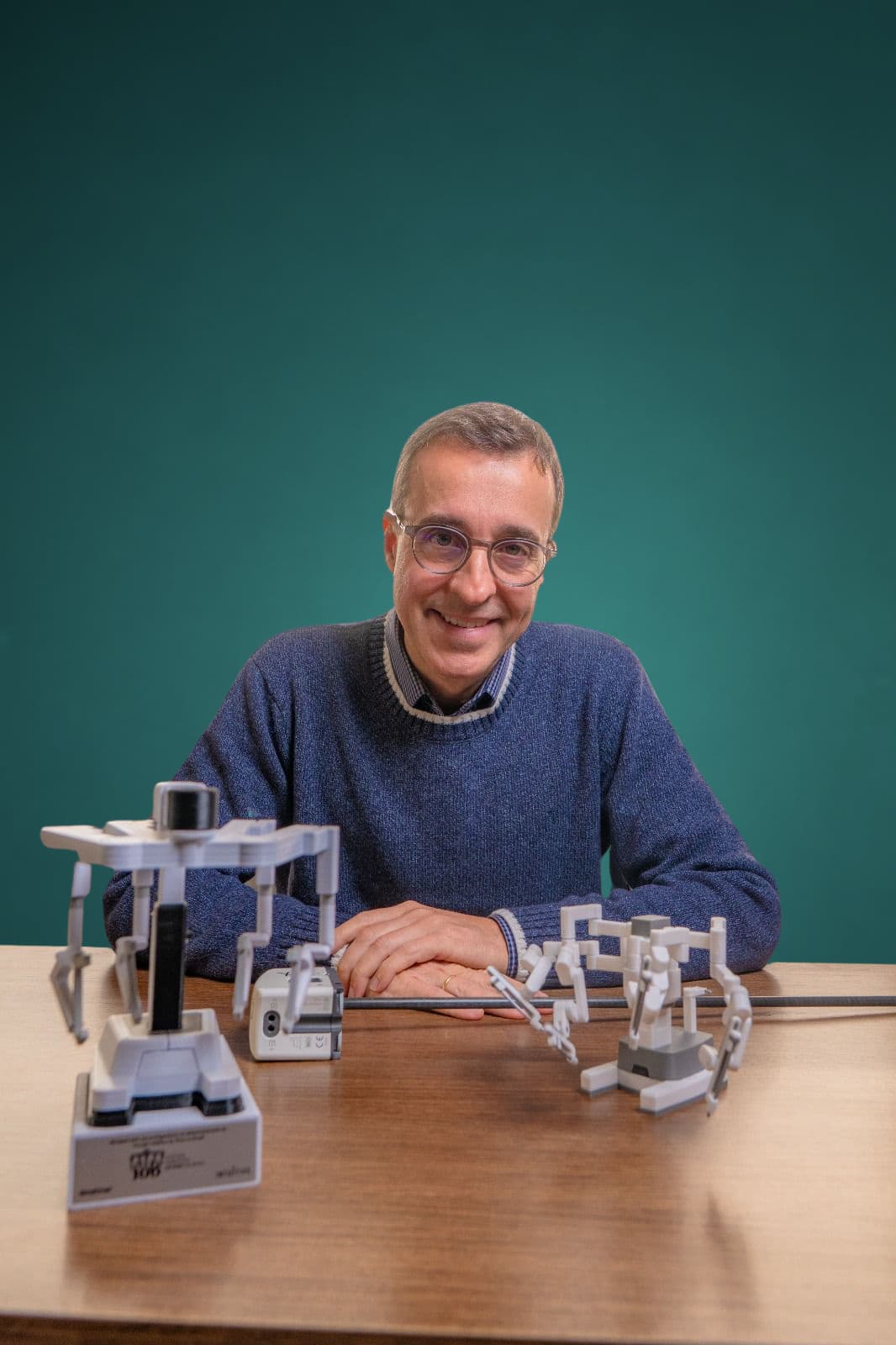 Dr. Fábio Lepper sentado à mesa do consultório com a plataforma robótica em miniatura, urologista em Joinville, CRM-SC 13.635